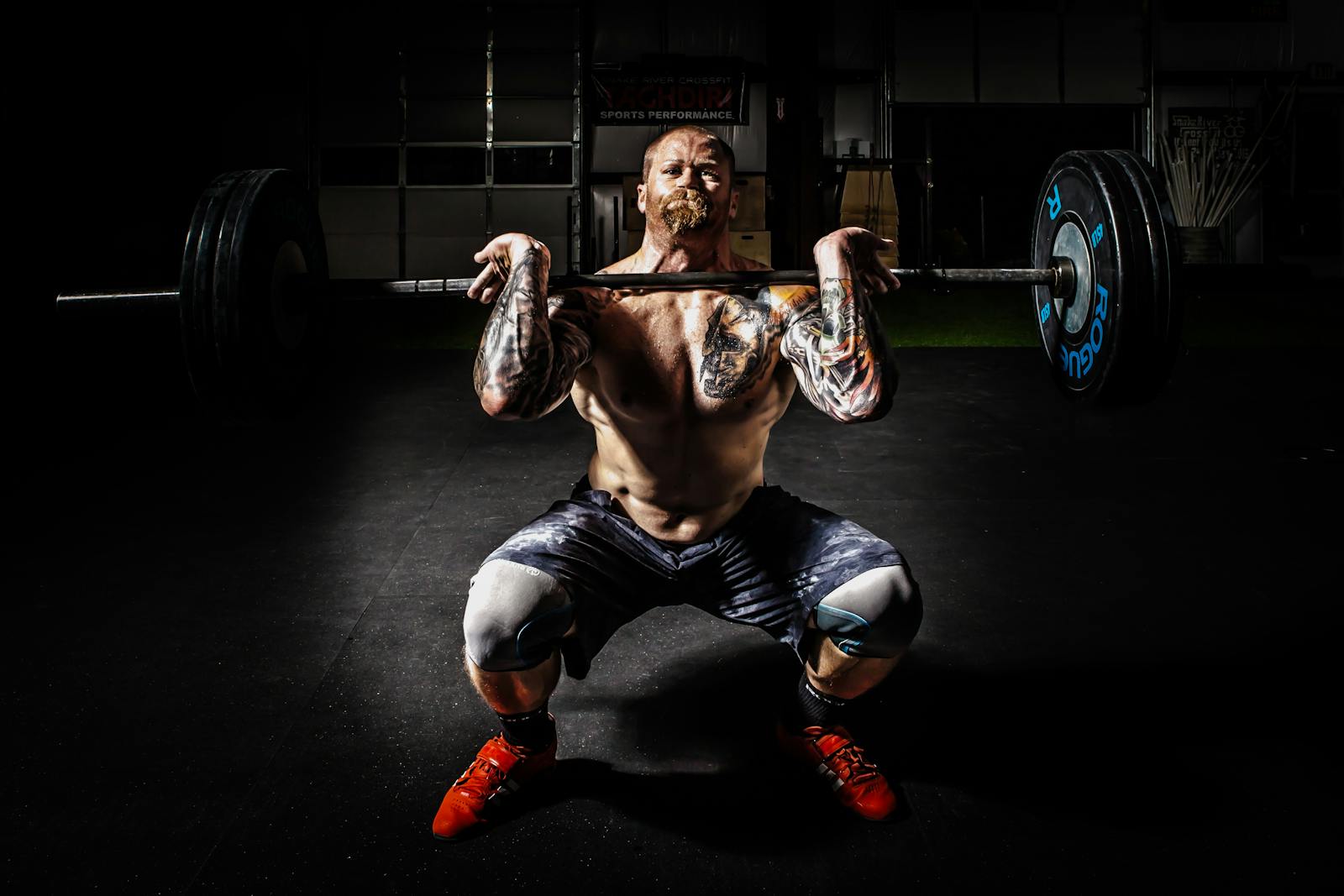 Man performing barbell squat exercise indoors.