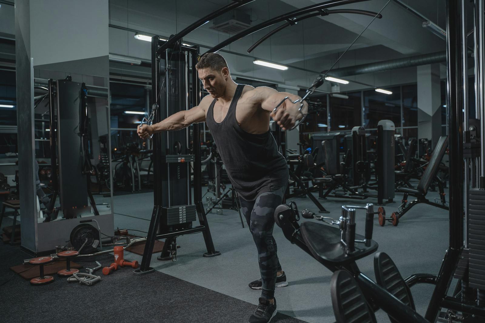 Man exercising on cable machine in gym.