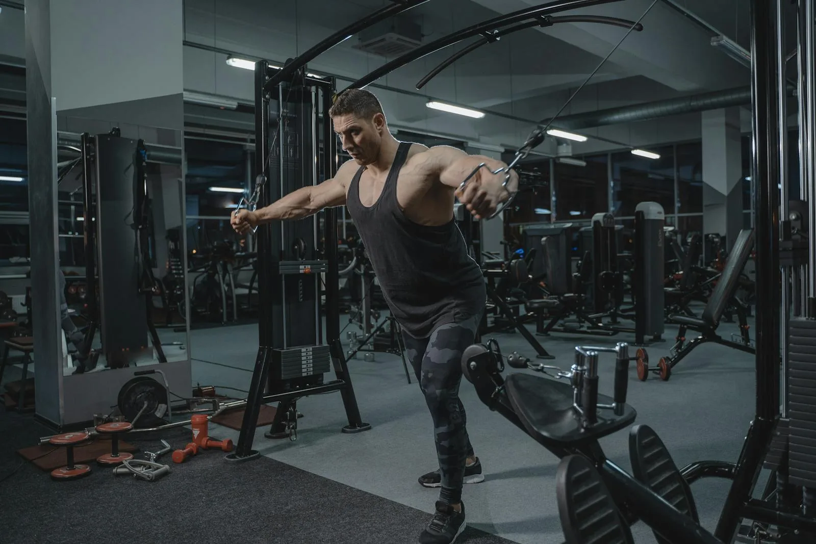 Man exercising on cable machine in gym.